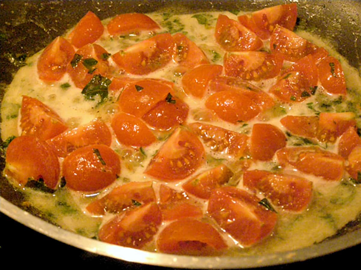 Tomatoes, butter, and basil in a skillet.