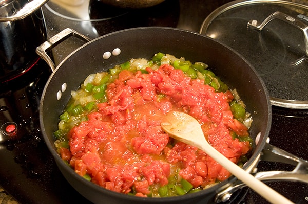 Tomatoes and seasonings added to skillet.