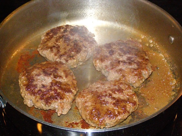 Burgers cooking on their second side.