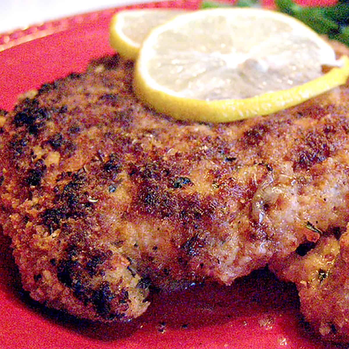 A serving of chicken piccata on a red plate.