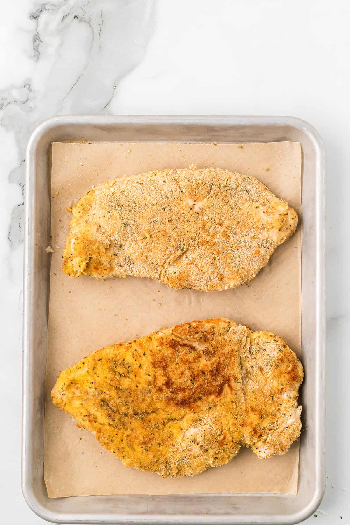 Browned chicken breasts on a baking sheet.