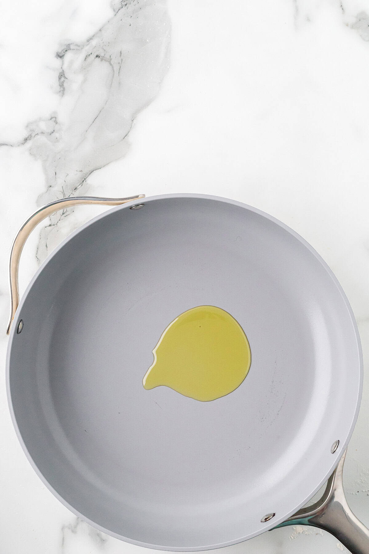 Olive oil heating in a skillet.
