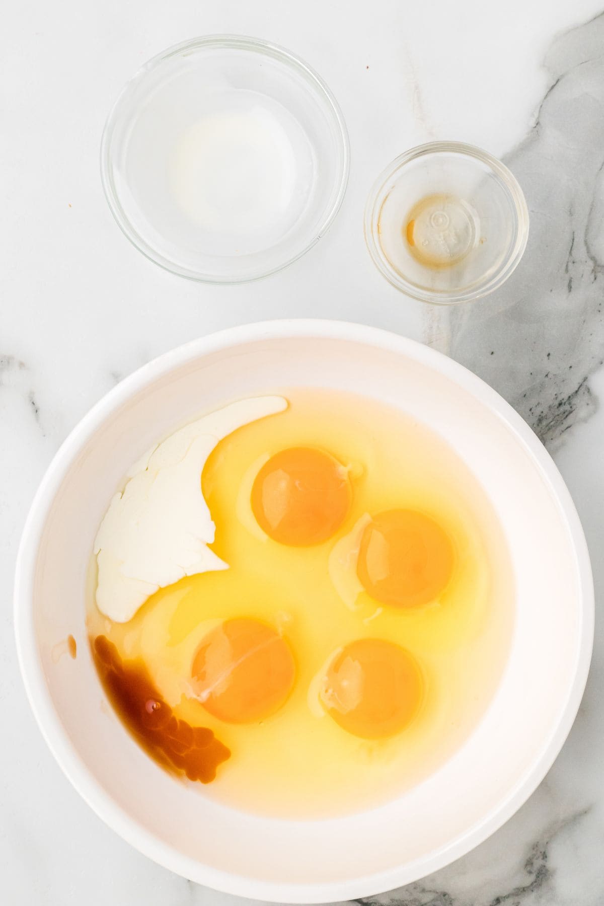 Half-and-half and vanilla added to eggs in a mixing bowl.