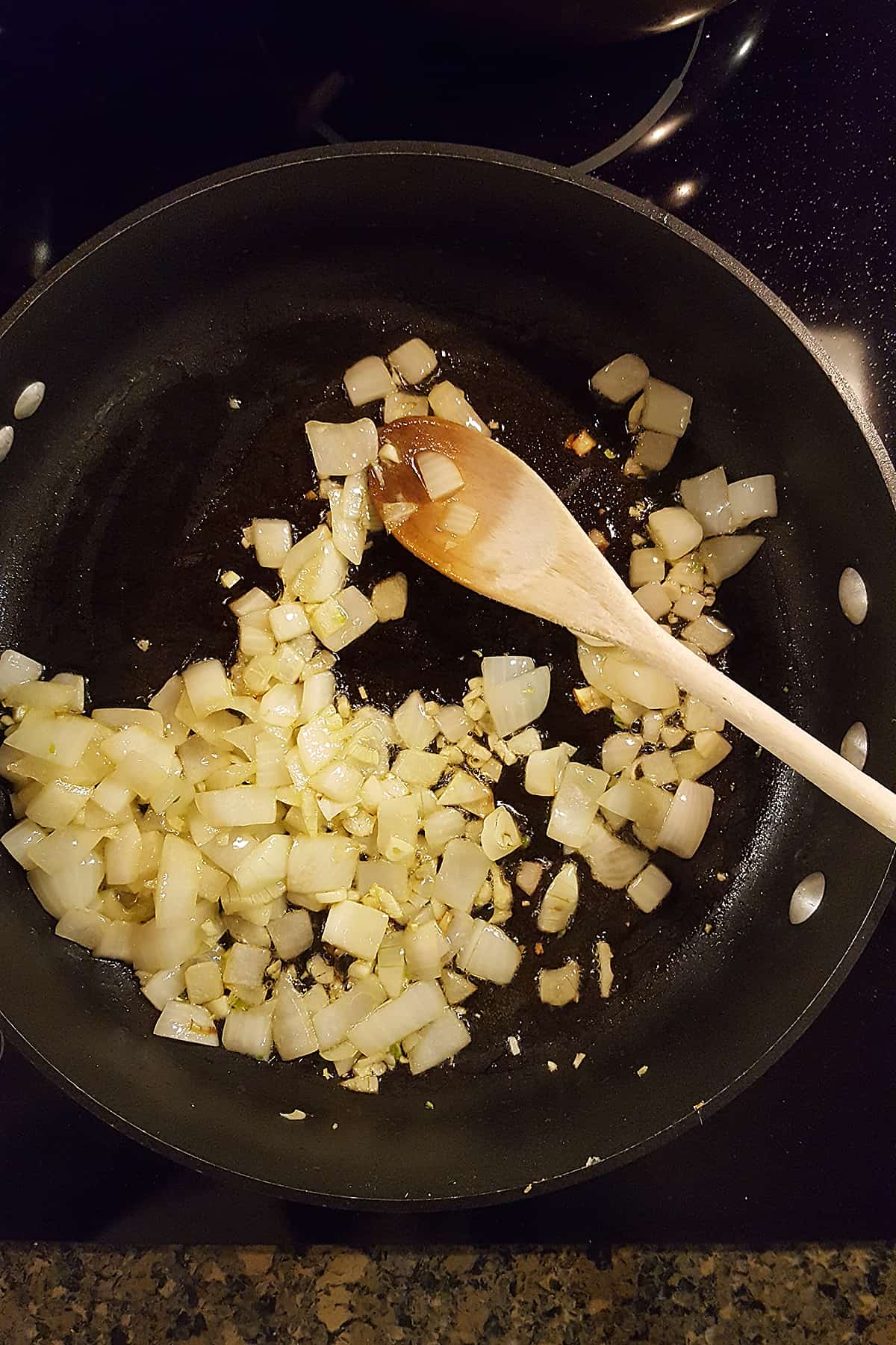 Saute pan with olive oil, garlic, and onions cooking.
