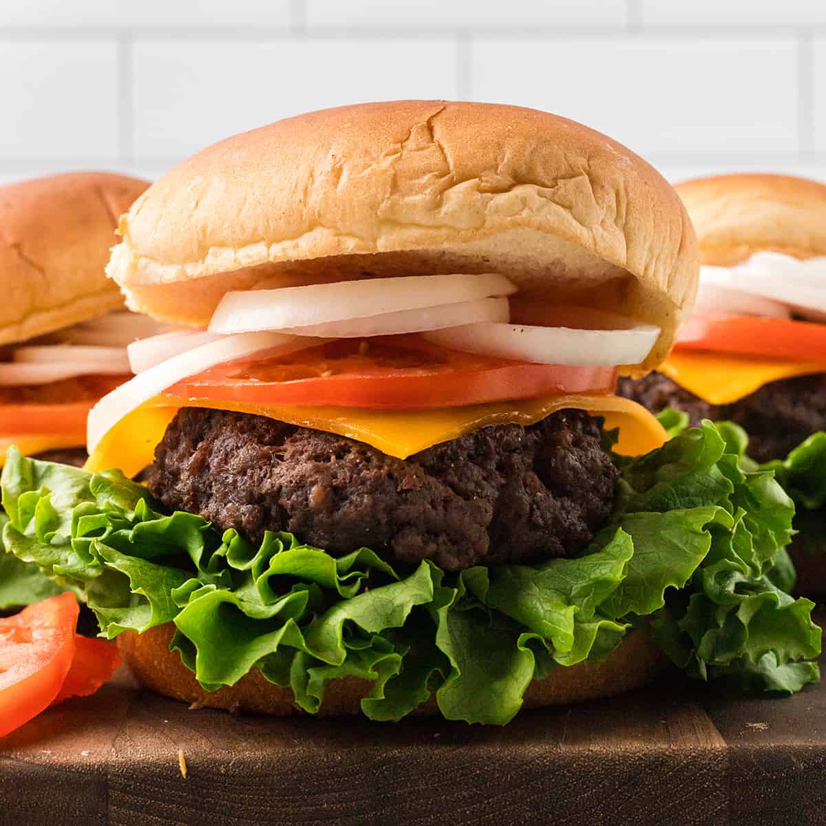 A burger on a bun with lettuce, tomato, cheese, and onions.