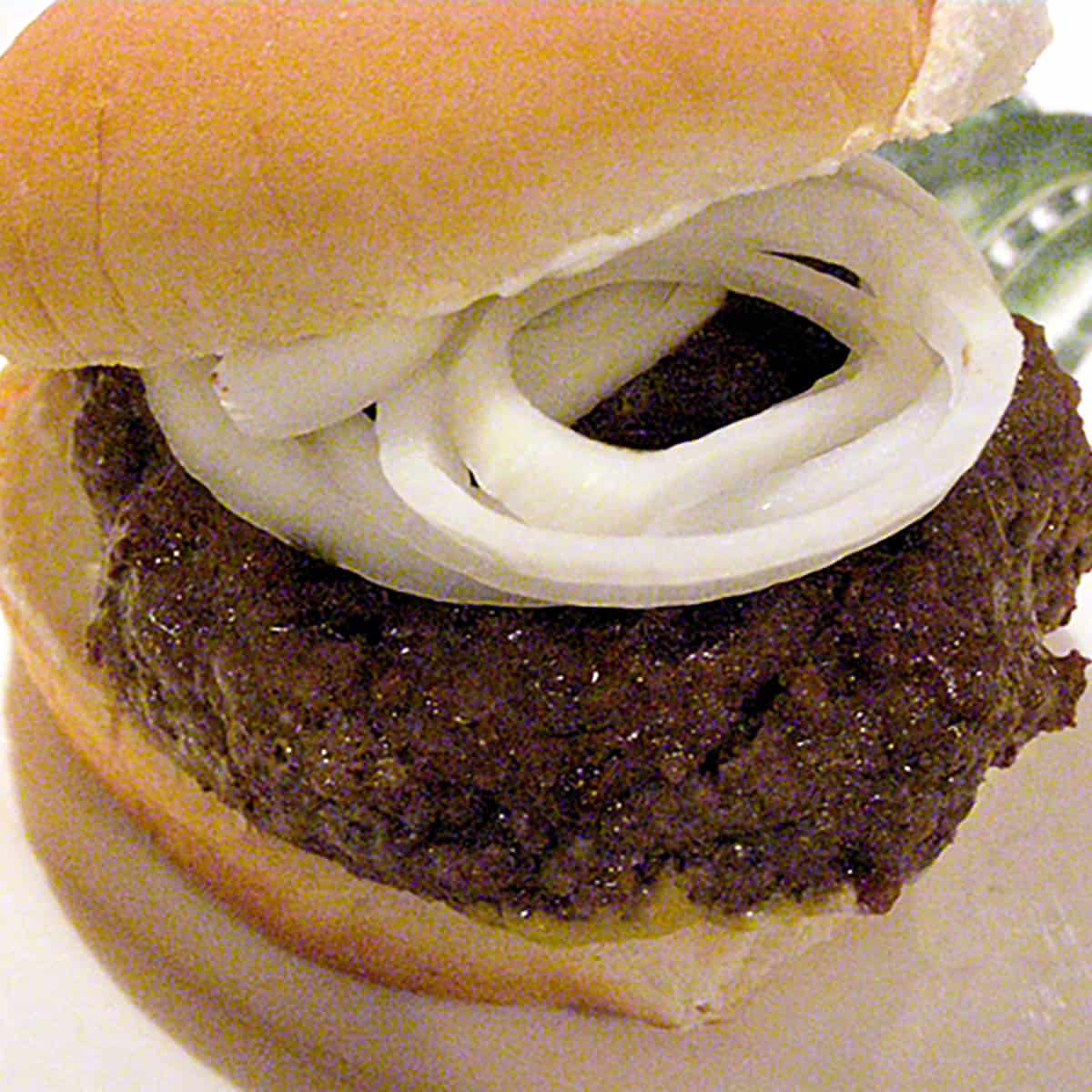 A burger on a bun with onions.