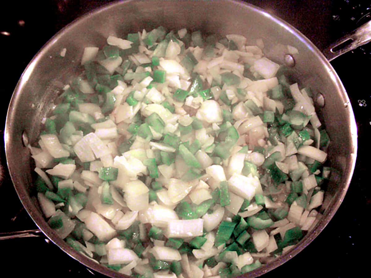 Onions and peppers cooking in a frying pan.