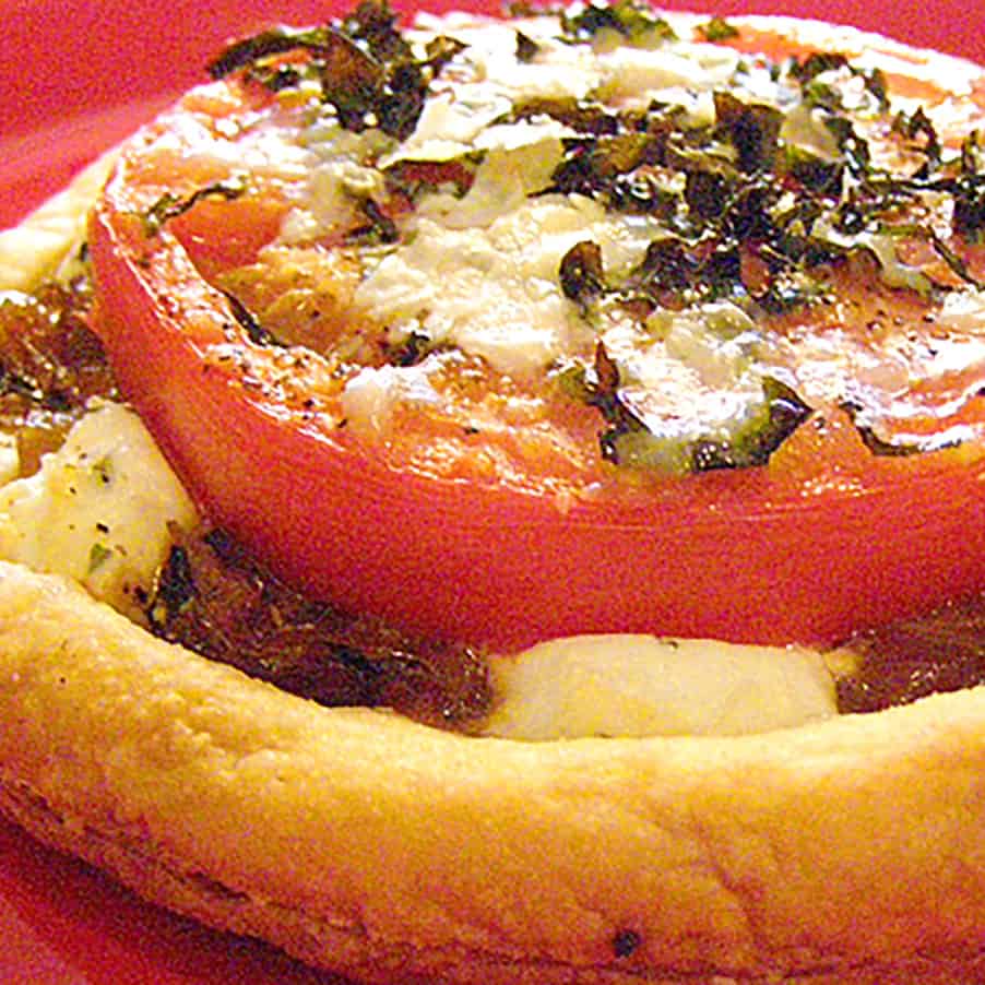 Finished tomato goat cheese tart on a red plate.