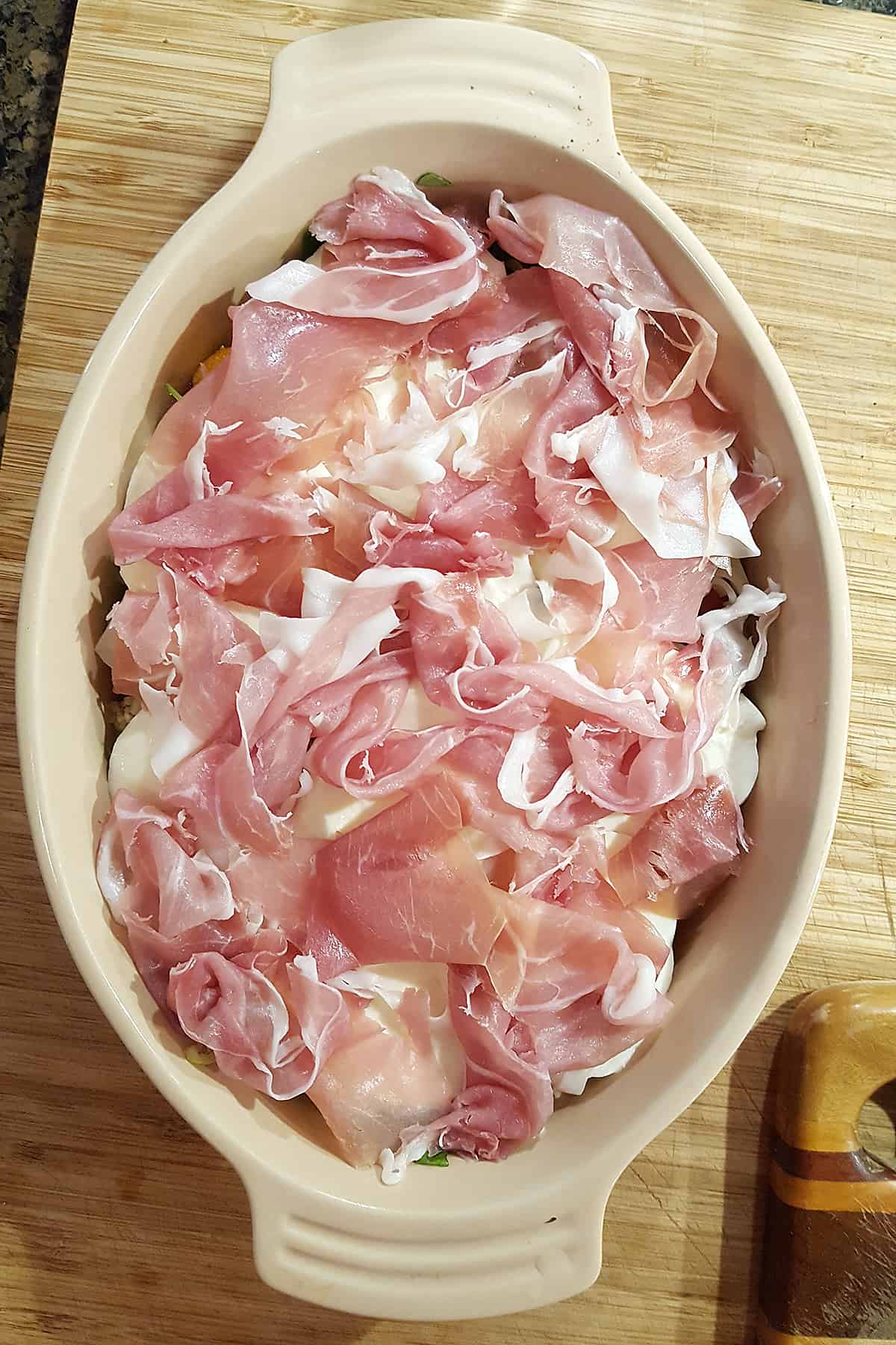 Shredded prosciutto over mozzarella, tomatoes, herbs, onions, and garlic