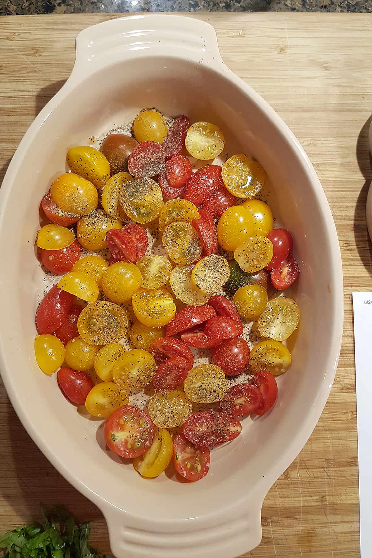 Ovenproof baking dish with halved cherry tomatoes sprinkled with salt and pepper