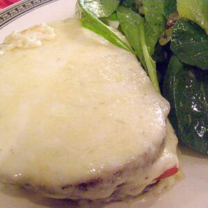 Finished croque monsieur on a plate with salad on the side.