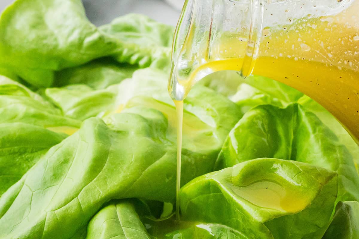 Vinaigrette being poured onto salad greens.