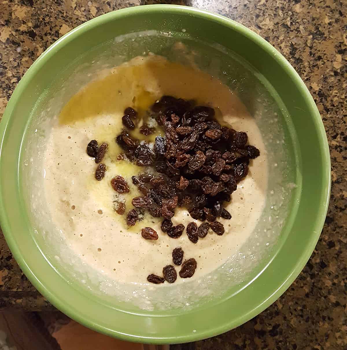Medium bowl with batter, raisins, and melted butter.