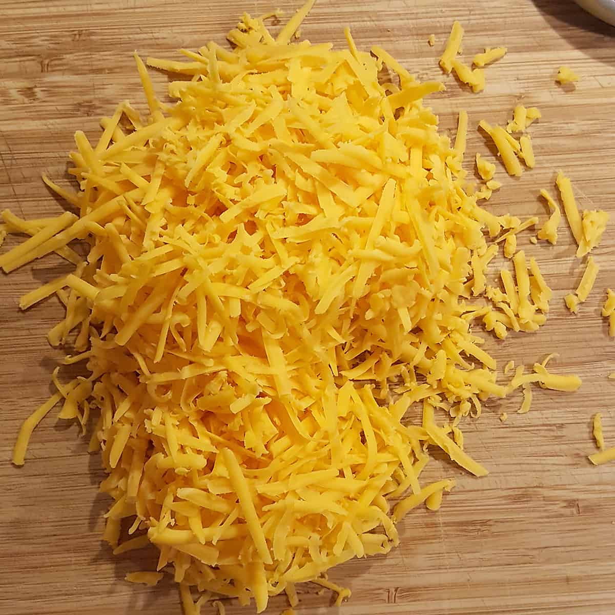 Grated Cheddar cheese on a cutting board.