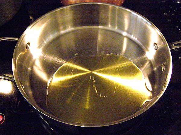 Olive oil heating in a large, deep skillet.