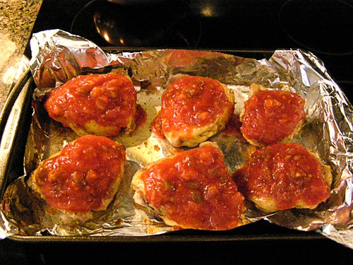 Partially cooked chicken thighs coated with salsa.