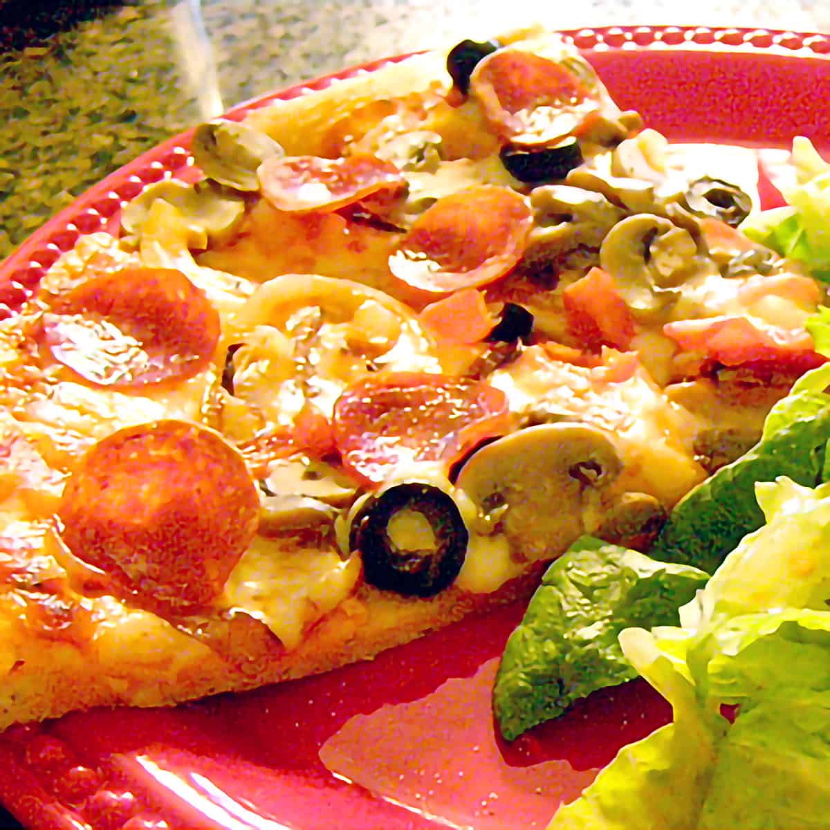 A slice of pizza on a red serving plate.