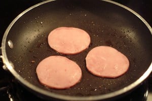 Canadian bacon warming in a skillet.