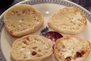 Buttered English muffins on a plate.