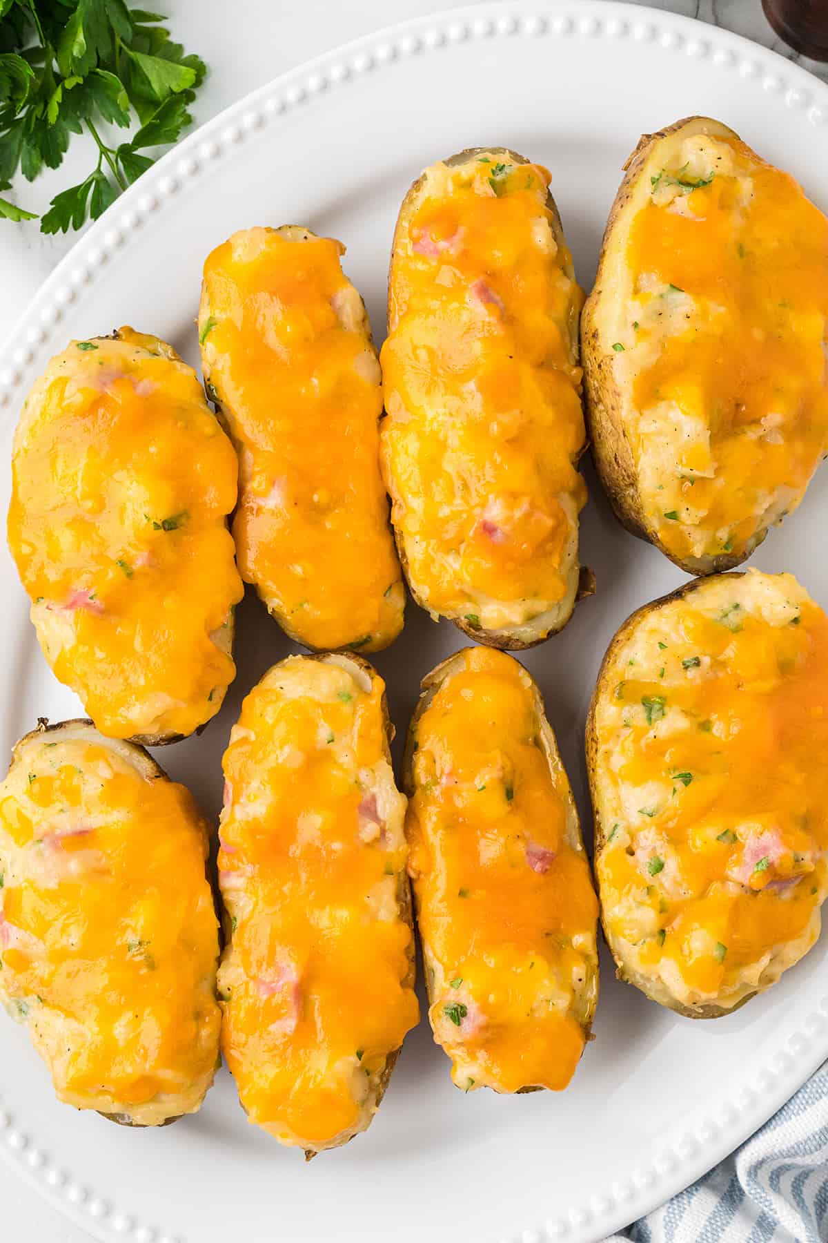 Ham and cheese stuffed potatoes on a white plate.