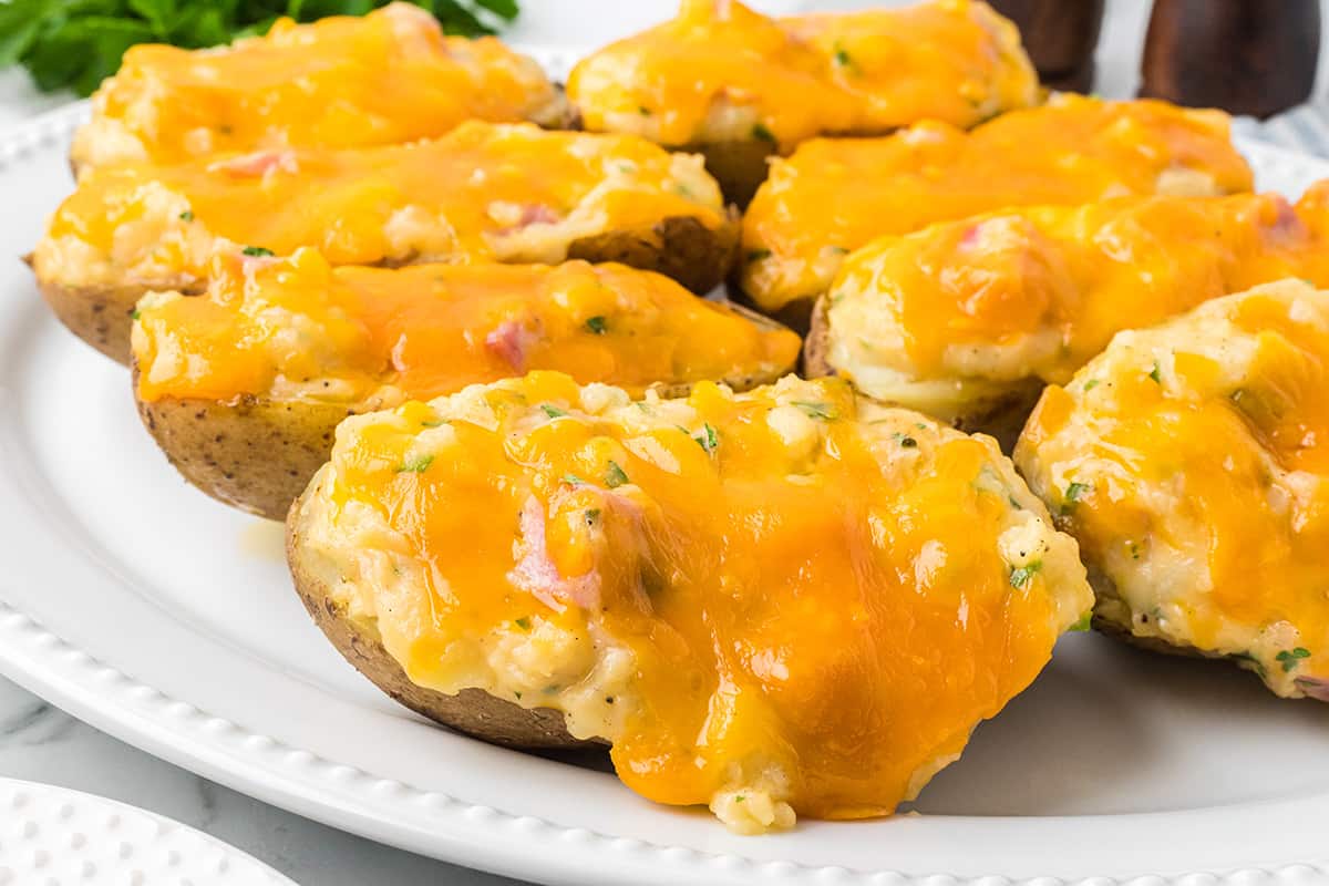 Ham and cheese stuffed potatoes on a white plate.