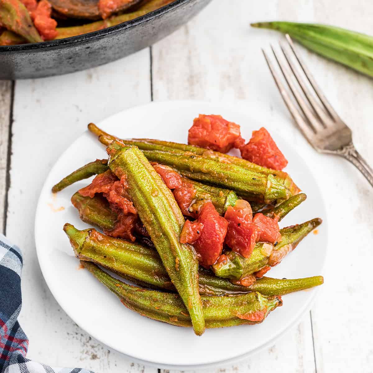 A serving of okra and tomatoes on a white plate.