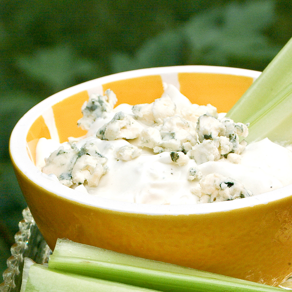 Blue cheese dip in a decorative bowl with celery sticks alongside.