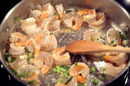 Garlic, green onions, and shrimp cooking in a skillet.