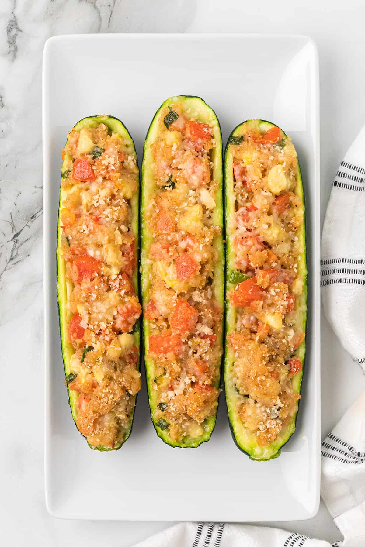 Three baked zucchini on a white plate.