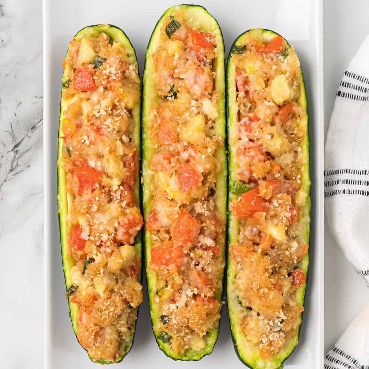 Three baked zucchini on a white plate.