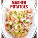 A dish of mashed potatoes with bacon, tomato, and green onions on a white plate; text overlay reads recipe name.