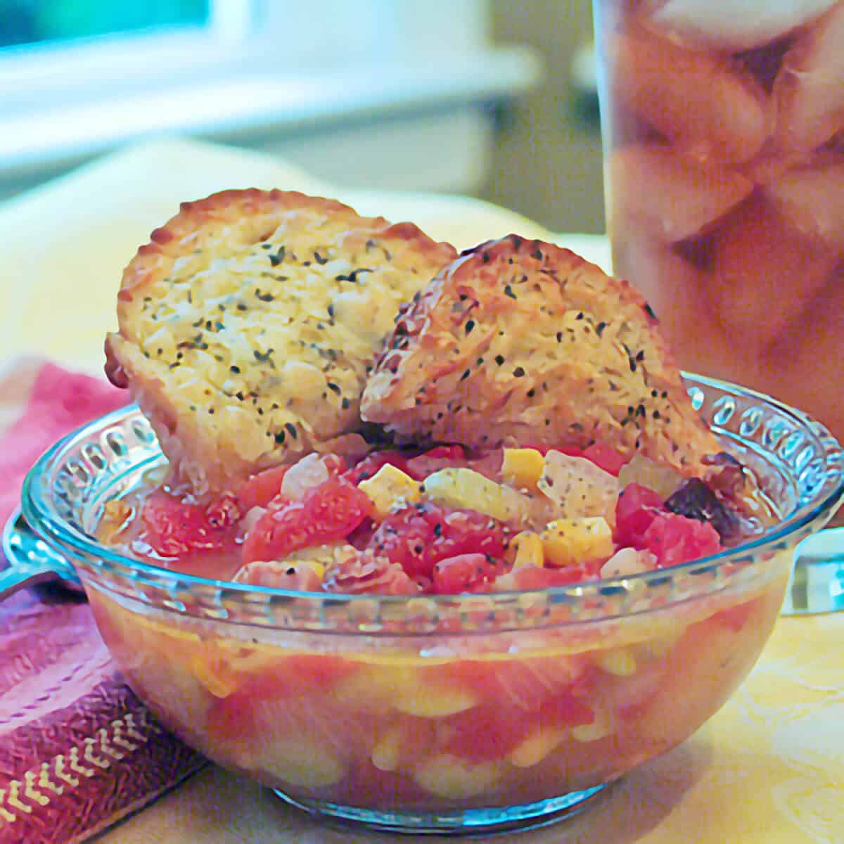 A serving of ham bone soup in a clear bowl with garlic bread on the side.