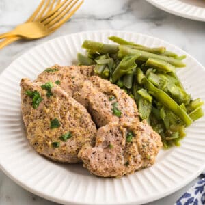 A serving of pork tenderloin with green beans on the side.