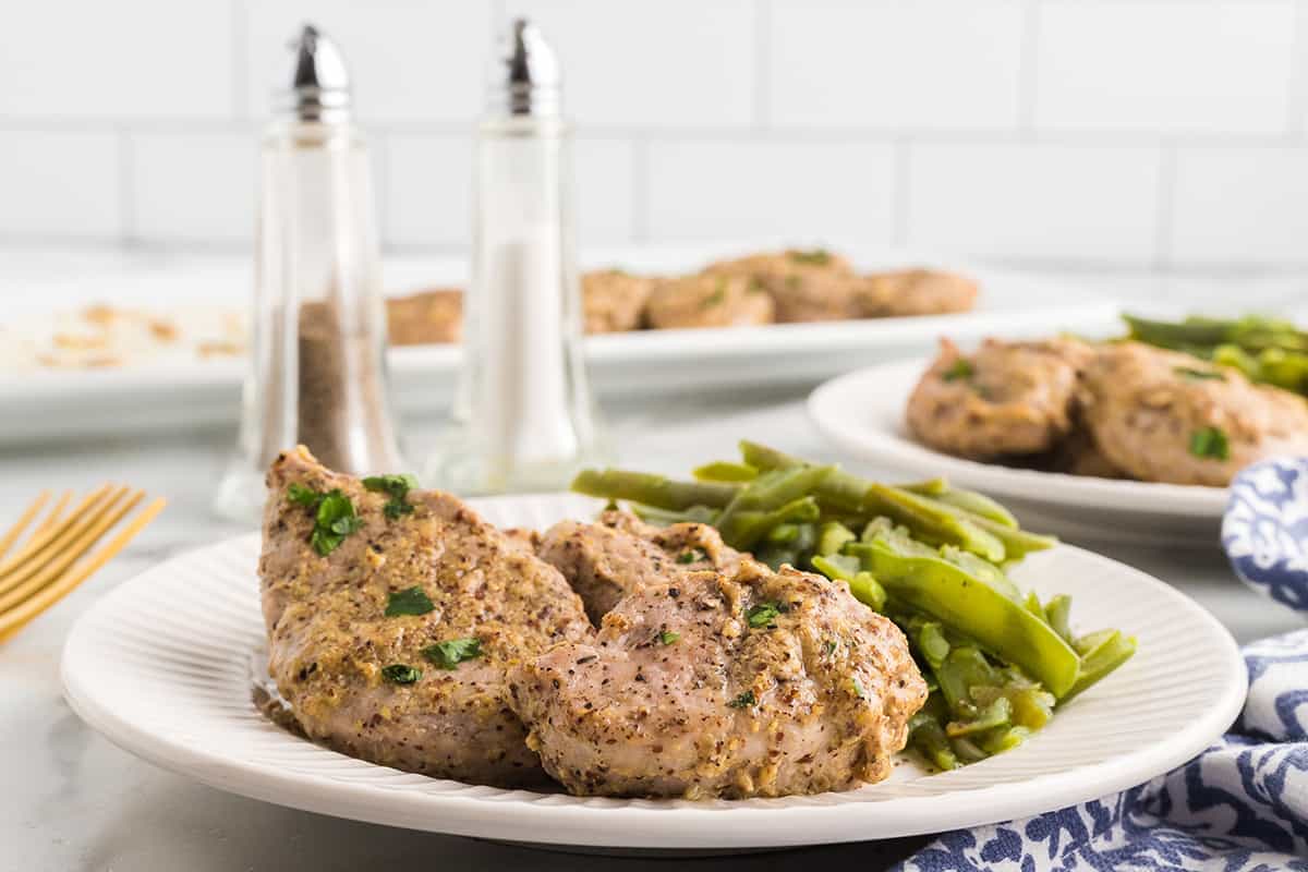 A serving of pork tenderloin with green beans on the side.