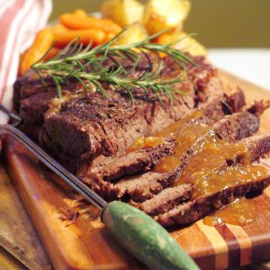 Pot roast sliced and presented on a serving board with gravy over top.