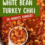 Close-up of white bean turkey chili in a pot with a ladle, surrounded by bowls of toppings.