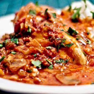 Bistro Chicken is chicken simmered in a tomato and mushroom sauce topped with cheese and bacon. Serve with mashed potatoes for a great weeknight dinner. https://www.lanascooking.com/bistro-chicken/