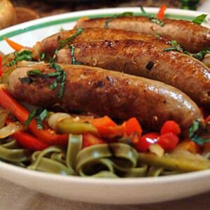 Italian SausagItalian sausage and peppers over pasta in a bowl.e and Peppers - a fantastic family meal. https://www.lanascooking.com/italian-sausage-and-peppers