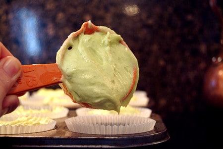 Filling paper cupcake liners with batter.