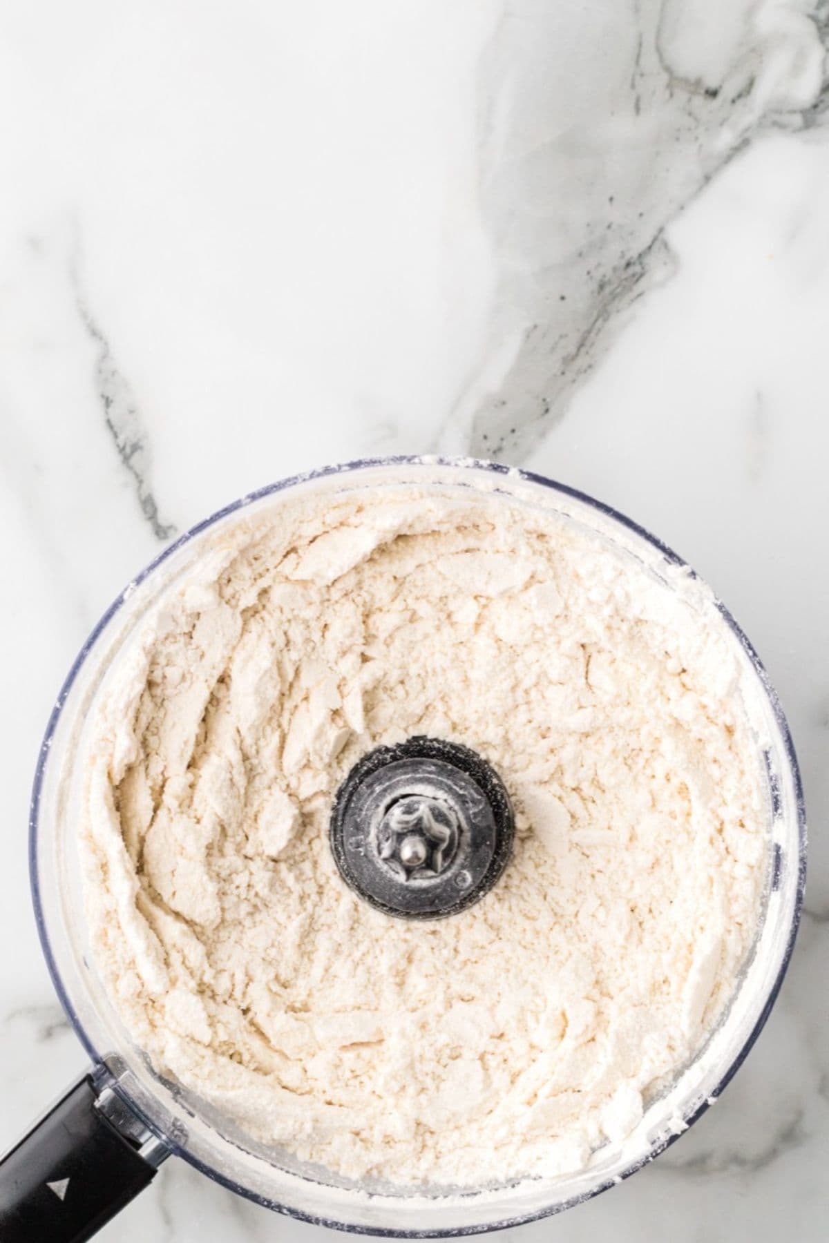 Flour and butter being combined in a food processor.