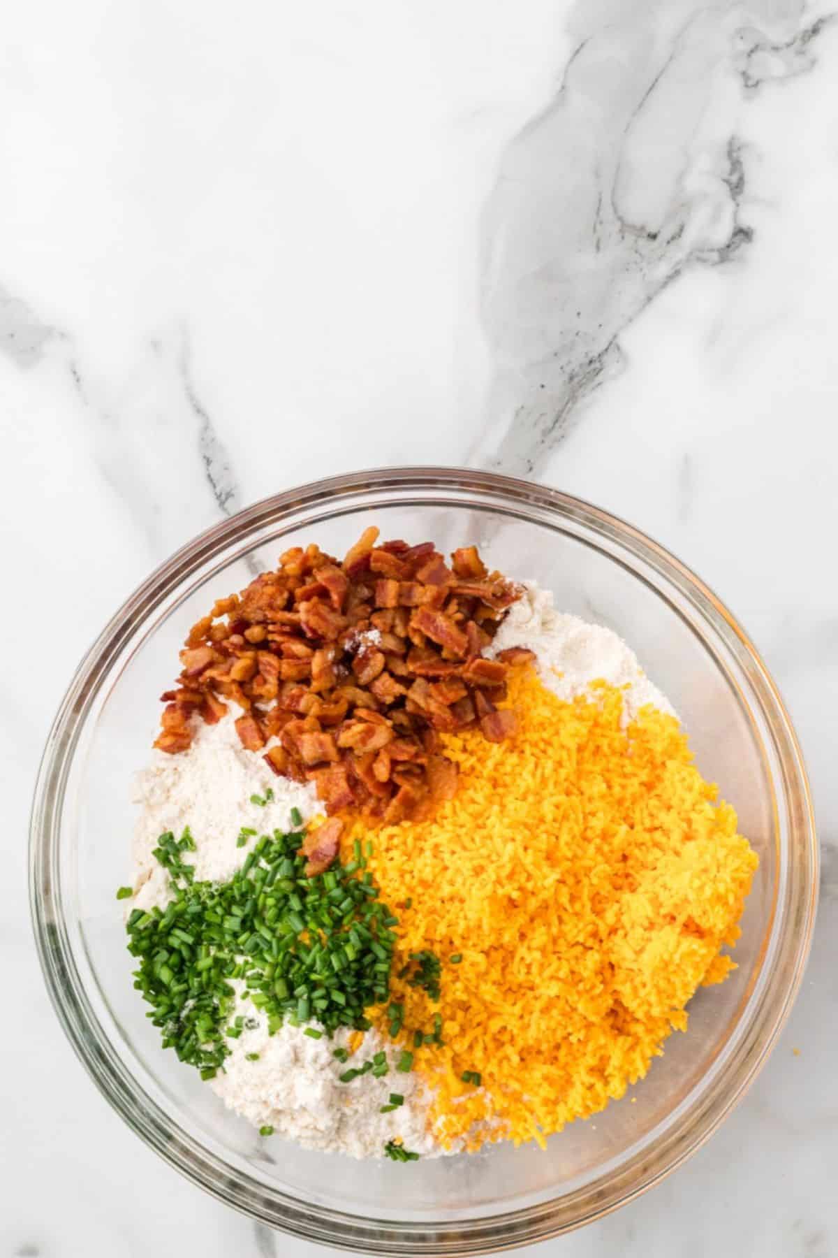 Flour-butter mixture, cheese, chives, and bacon in a mixing bowl.