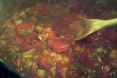 Adding stewed tomatoes to the pan.