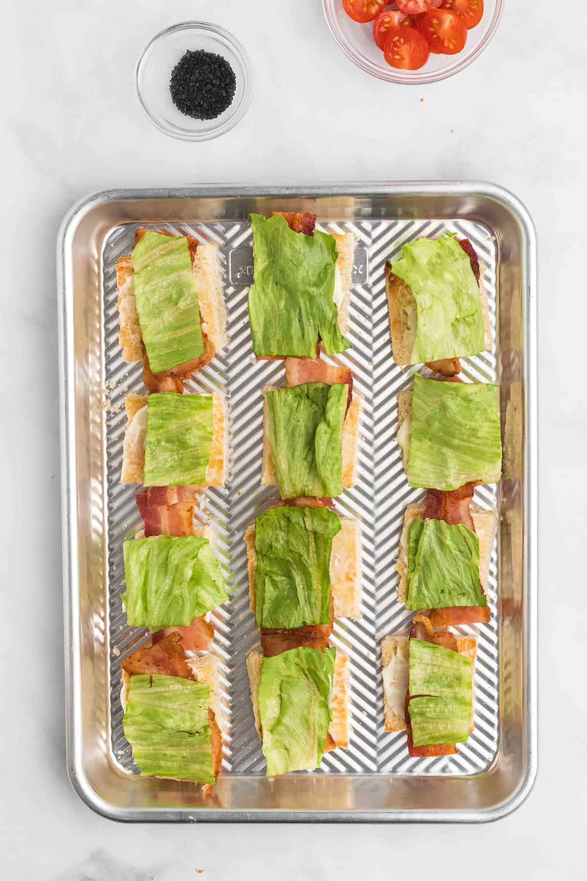 Lettuce pieces added on top of bacon.