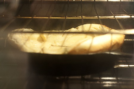 Pancake cooking in a skillet in the oven.