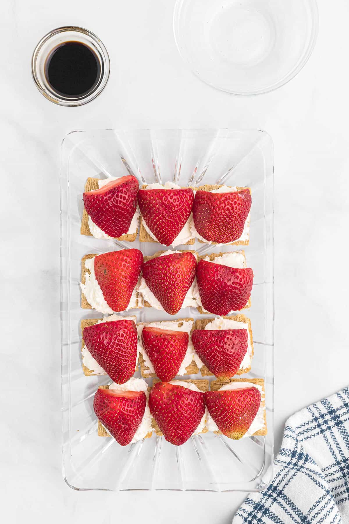 Crackers topped with cream cheese and strawberry halves.