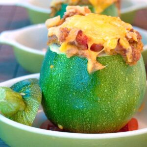 Baked stuffed 8-Ball Zucchini in a green serving dish.