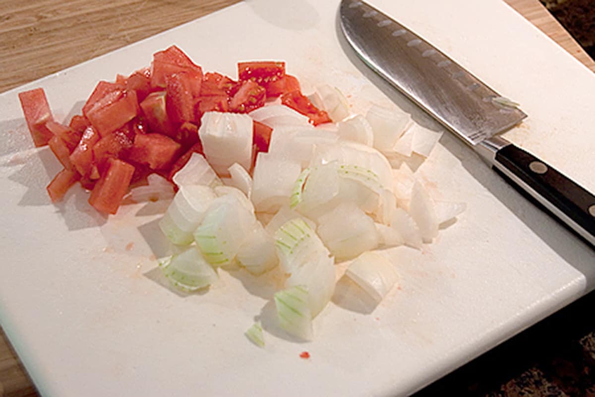 Chopped tomato and onion on a cutting board.