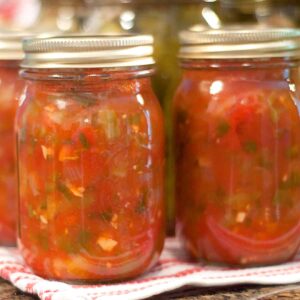 Jars of finished basic salsa lined up on a kitchen towel.