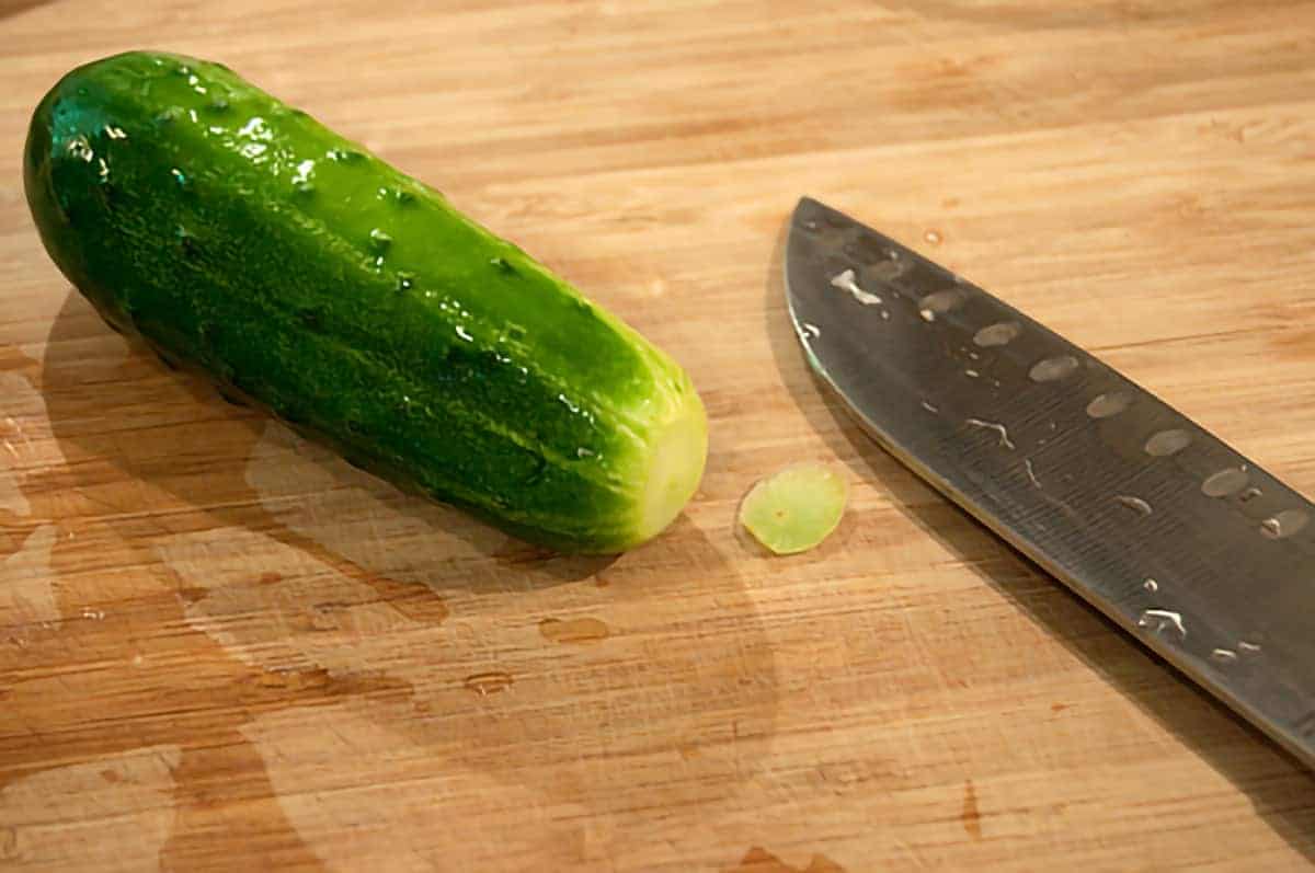 Cutting board with a cucumber and knife.