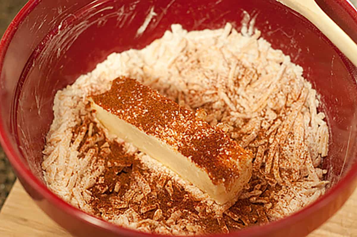 A red mixing bowl containing flour, a stick of butter, and spices.